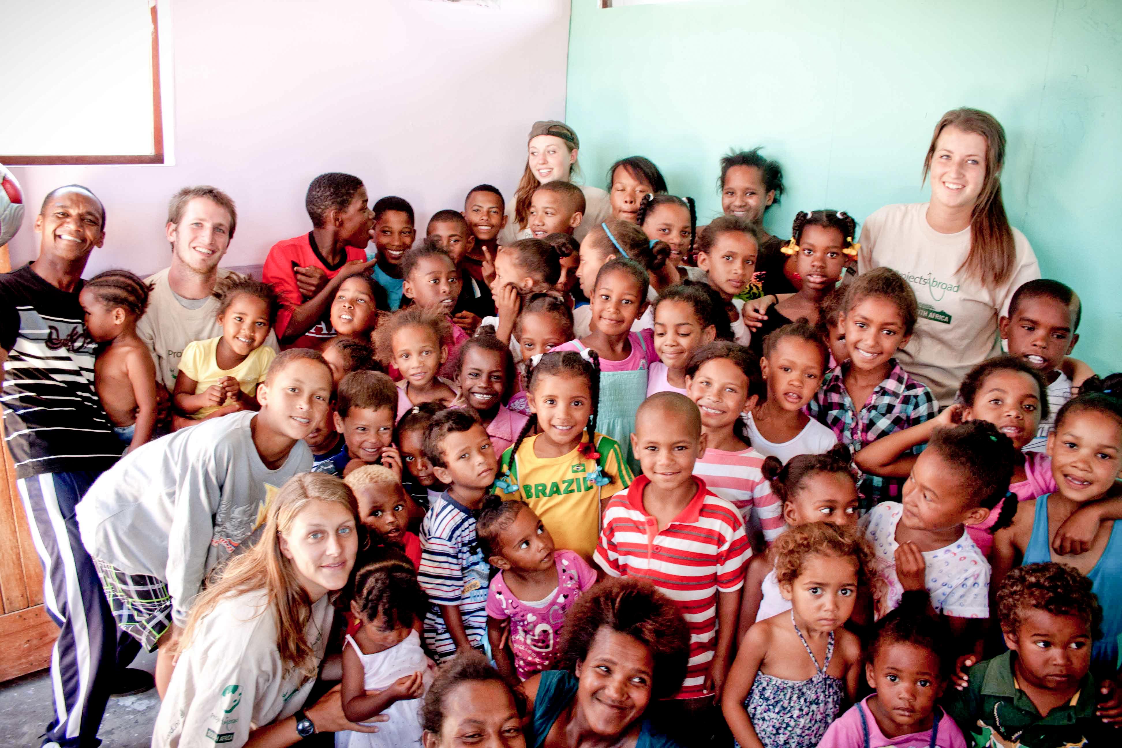 Projects Abroad volunteers with children in South Africa pose for a photo in a care centre during Childcare placement. Childcare volunteers with children in South Africa pose for a group photo during a care and community project.